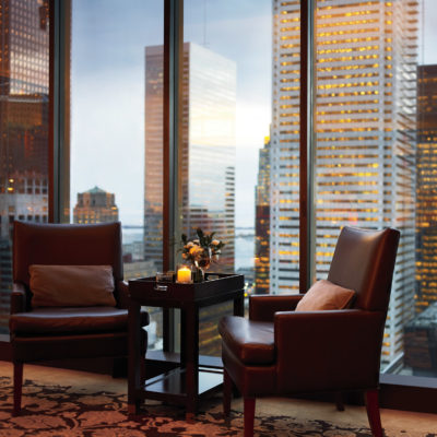 Dos sillas de cuero de lujo ubicadas frente a ventanas del piso al techo con vista a la ciudad
